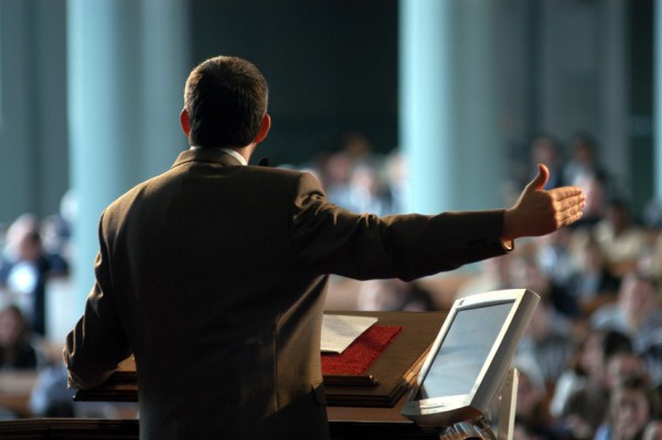 Preacher at pulpit preaching, photo taken from behind